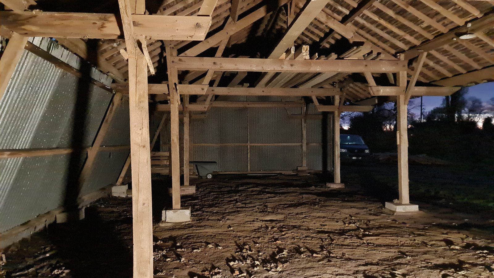 Intérieur du hangar : charpente bois et poteaux repris sur plots béton avant équipement en séchoir
