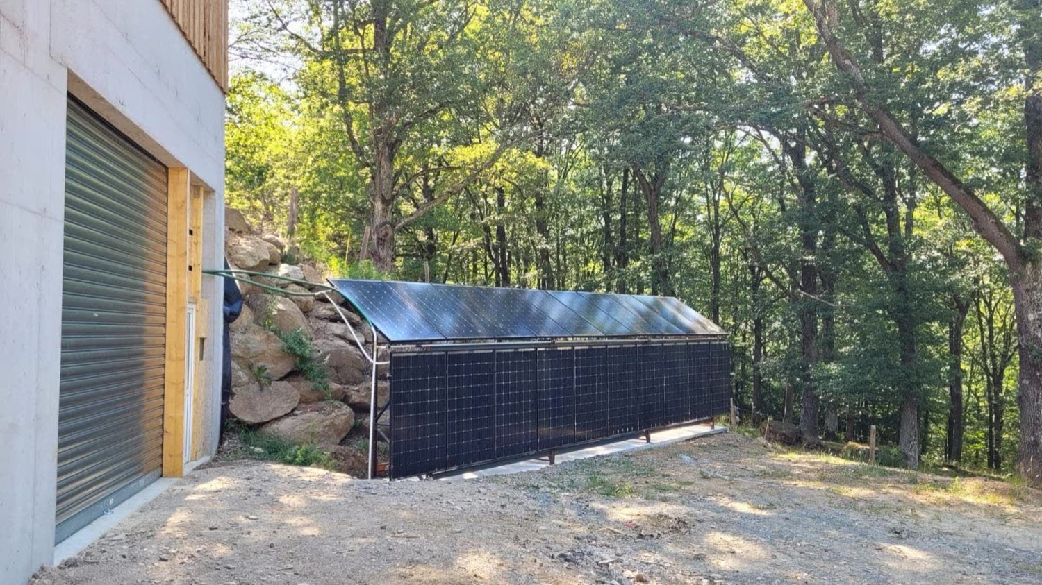Rangée de capteurs solaires à air installés au sol le long d'un bâtiment agricole